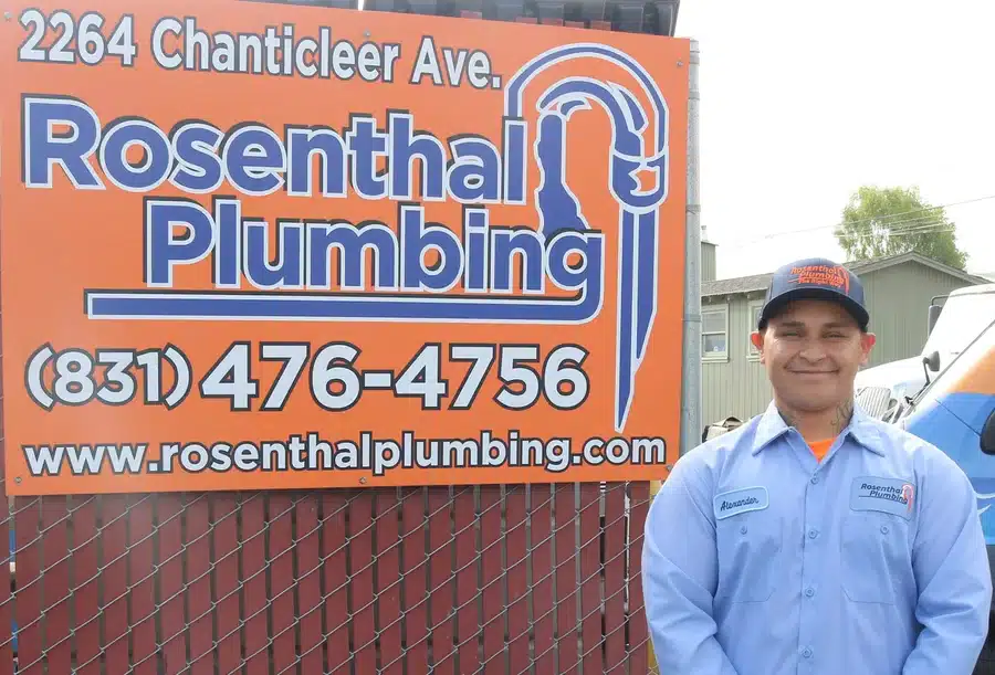 Alexander, a Rosenthal Plumbing technician, smiling beside the company sign at their Santa Cruz, CA location